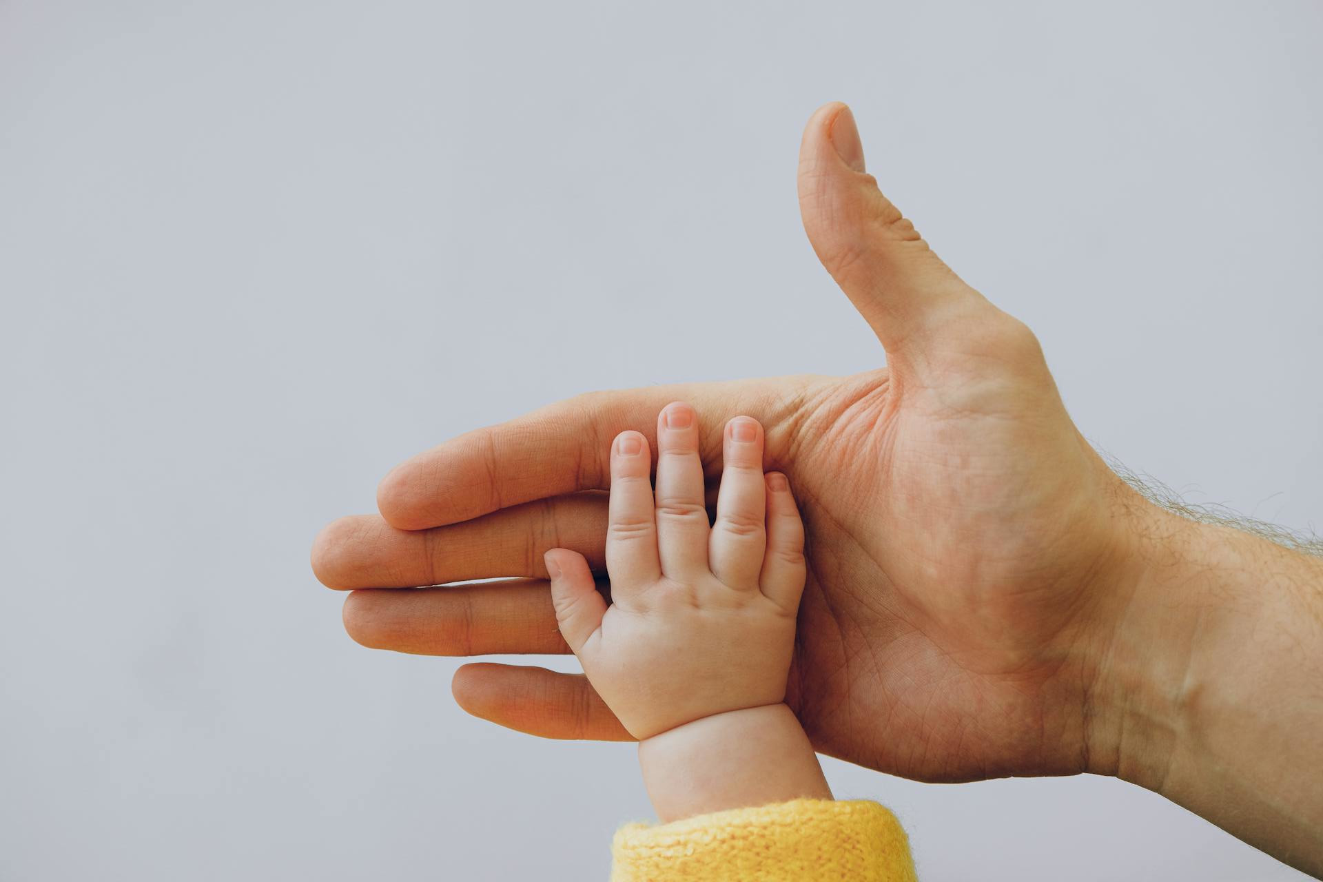 Pappas hand som möter ett barns hand.