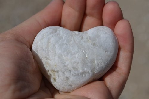 En hjärtformad vit sten på handen.