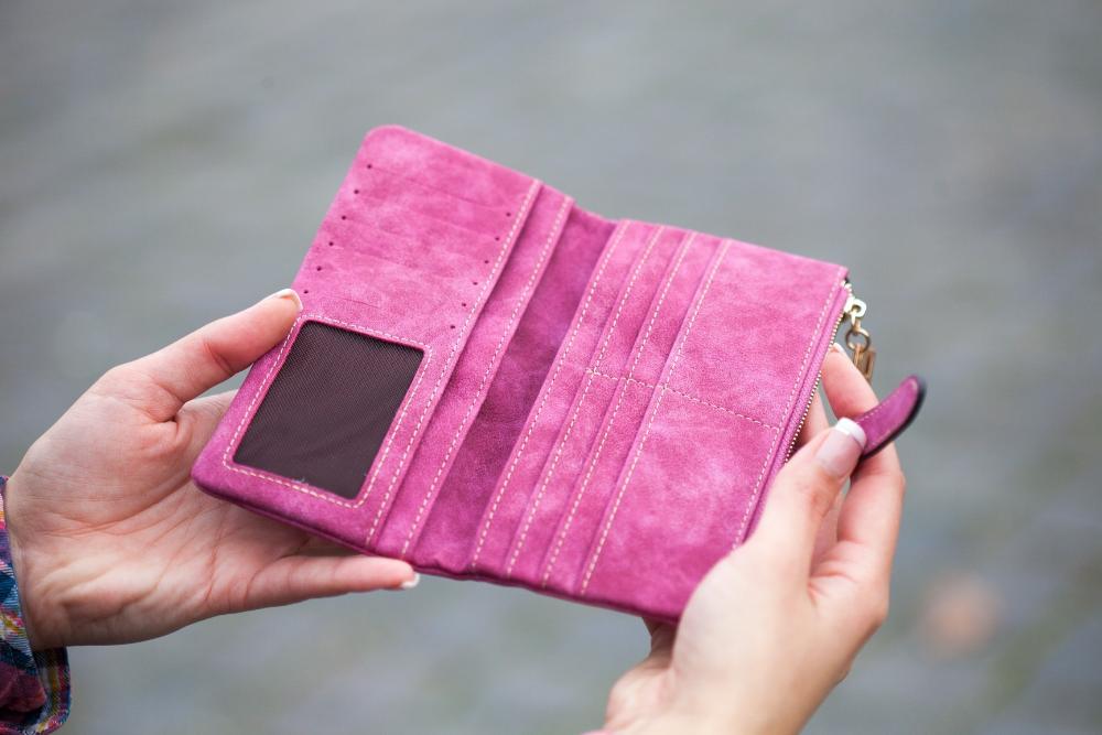 En tom rosa plånbok som två händer har öppnat.