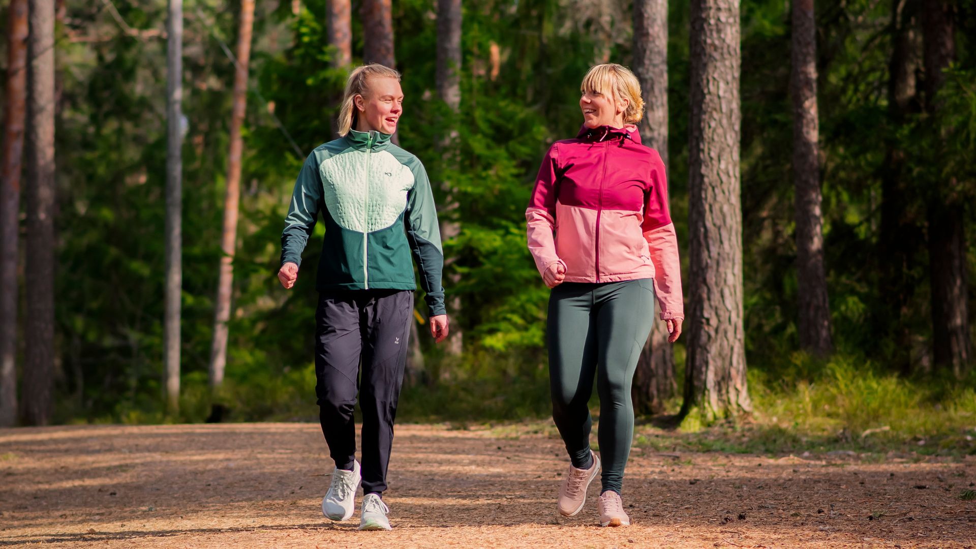 Två personer promenerar i skogen.