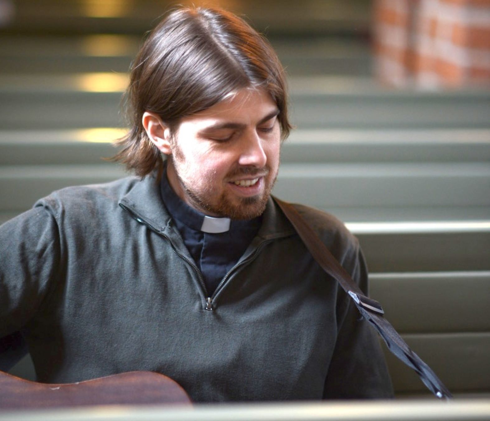 Porträtt ung man spelar gitarr i kyrka.