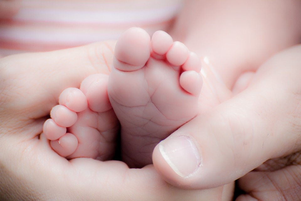 Babymassagekurs Babyfötter där en mamma masserar fötterna.