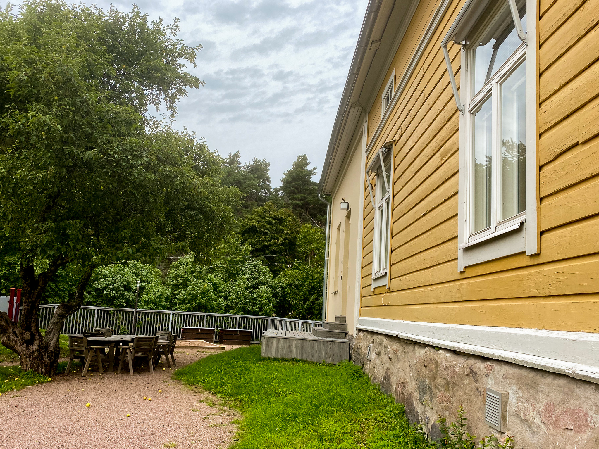 Gul träbyggnad, trädgård, bord, sommar.