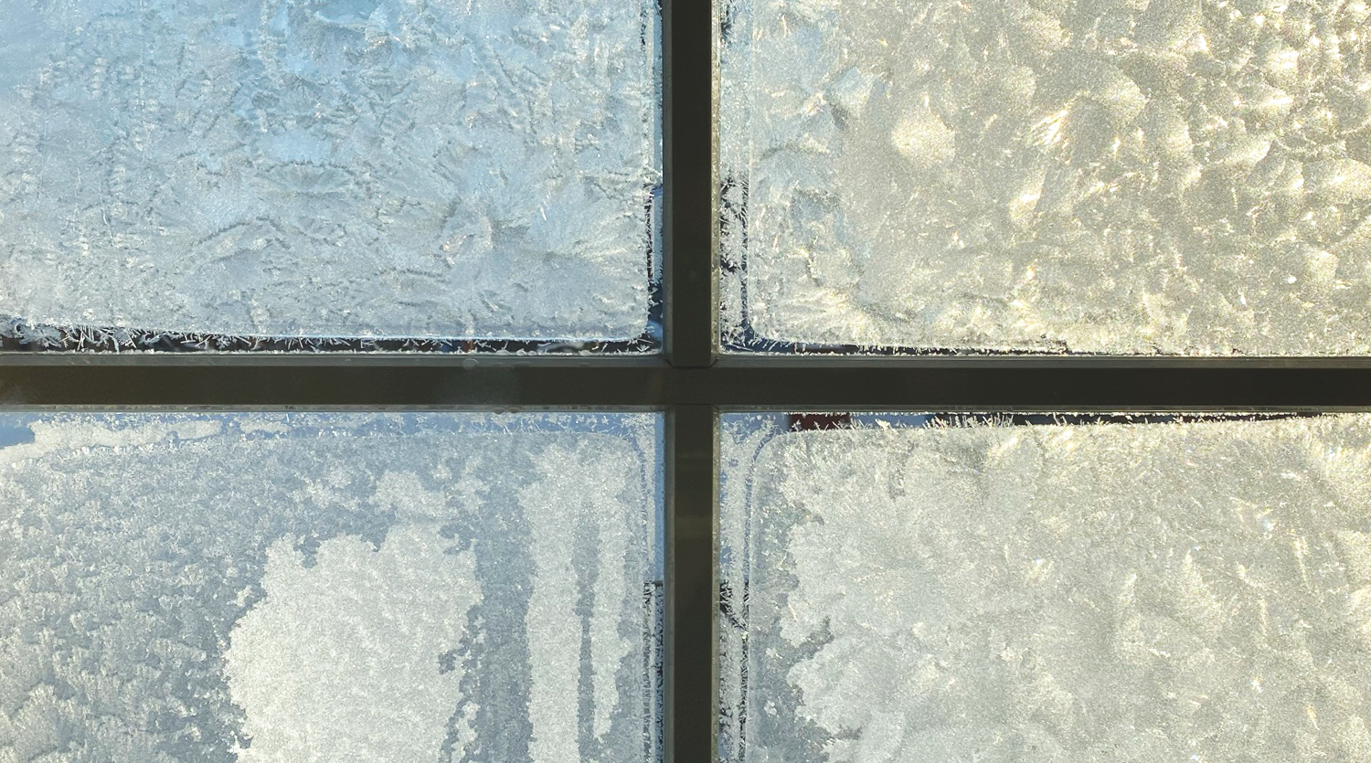 Fönsterruta med rimfrost och ett kors.