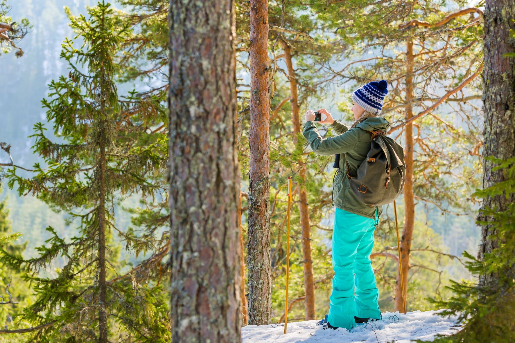 Ung person som fotar i vacker skog.