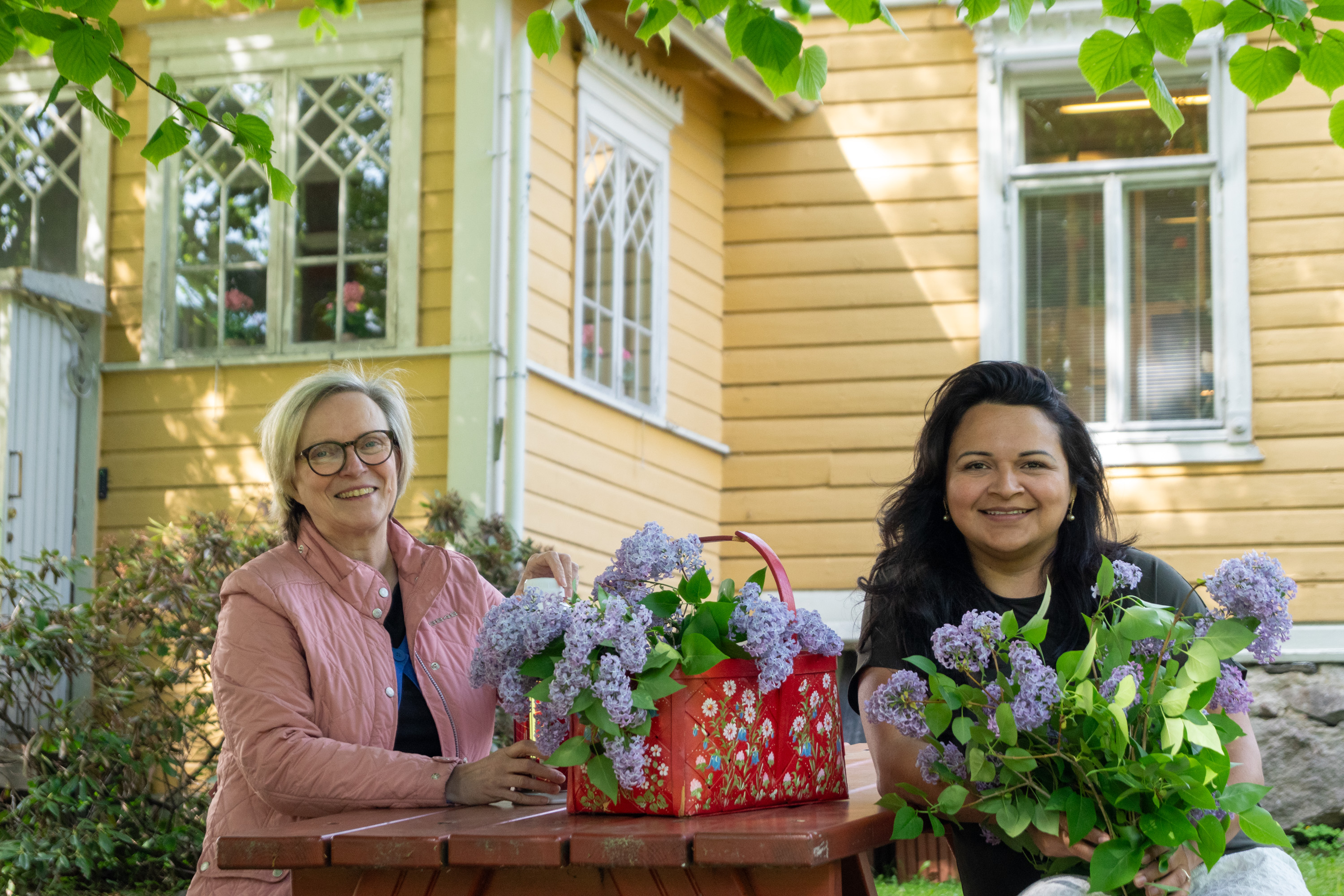 Två personer, blommor och trädgård.