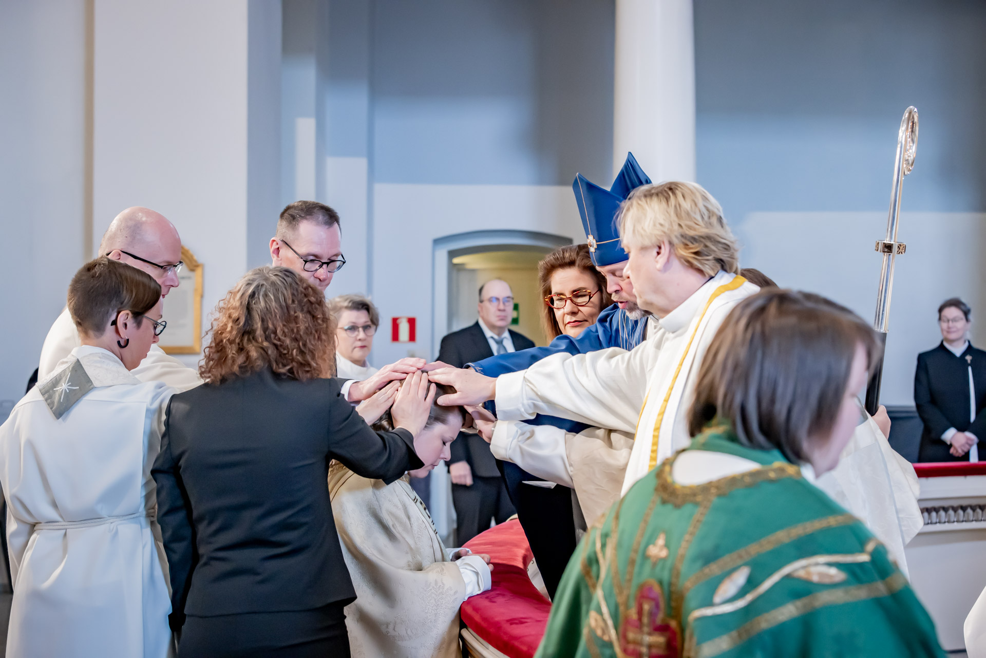 Människor välsignar präst kring altare.