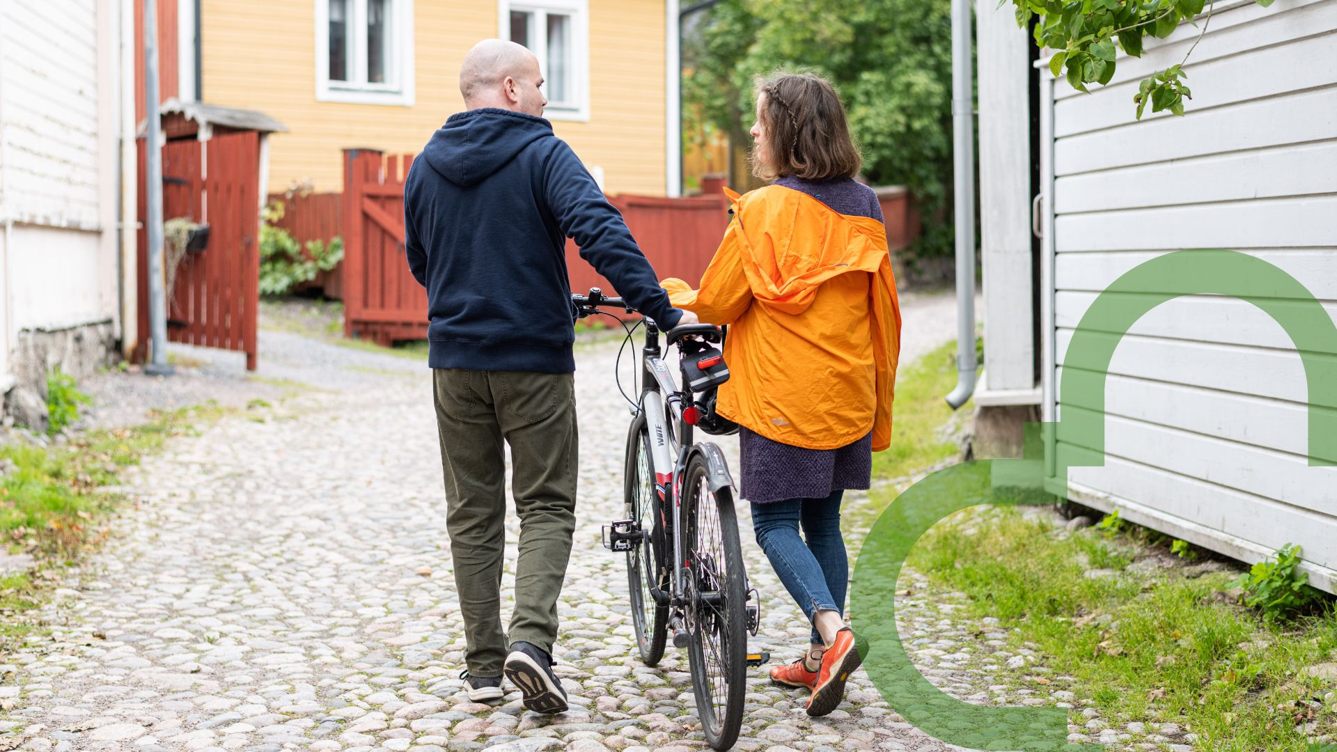 Ett par promenerar i idyllisk miljö, ena personen leder en cykel.